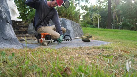 man starts a weed whacker machine at floor level