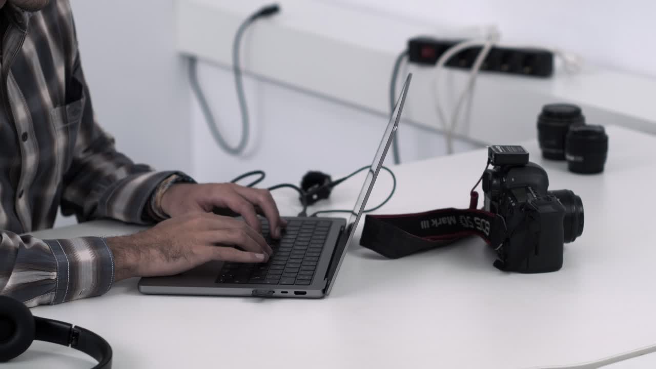 fotógrafo editando imágenes en una computadora portátil con dslr cerca
