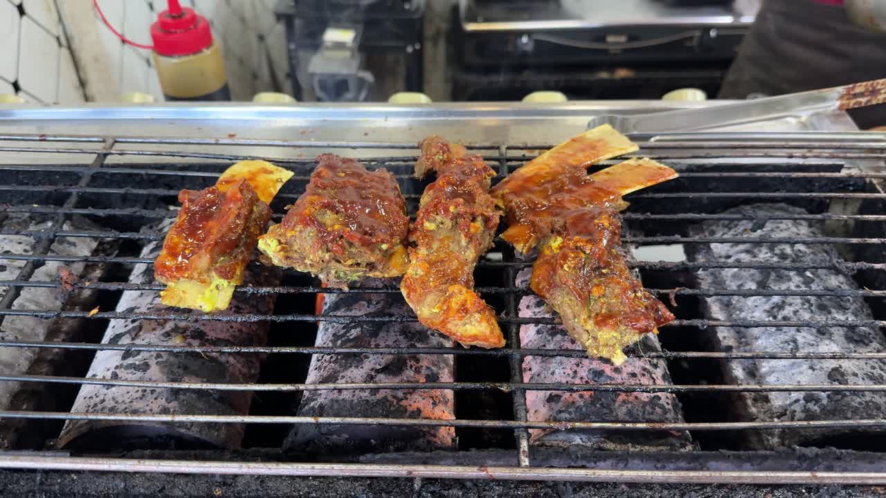 Deliziose costine marinate che cuociono su una griglia calda