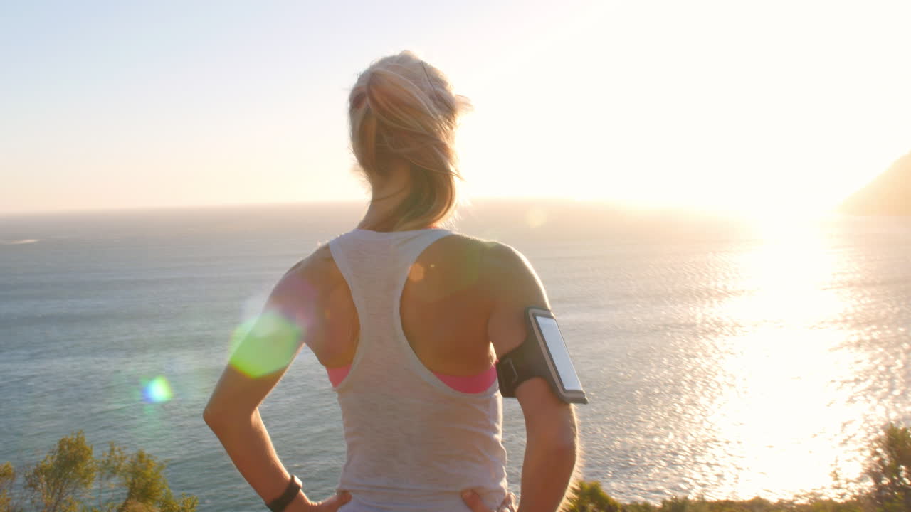 Giovane donna che ammira un panorama costiero dopo aver fatto jogging