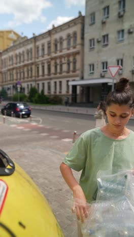 teenager recycling plastic bottles in a city street