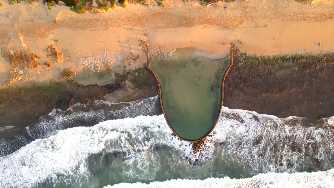 Top down aerial over Witsand marine tide pool as waves crash onto shore