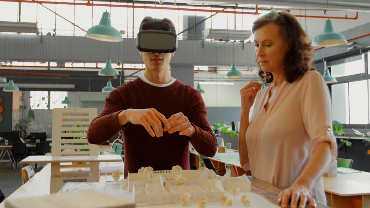 Executives discussing over architectural model while using virtual reality headset 4k