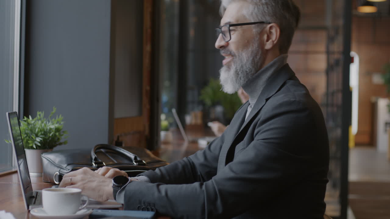 Forretningsmand, der arbejder på bærbar computer på en café