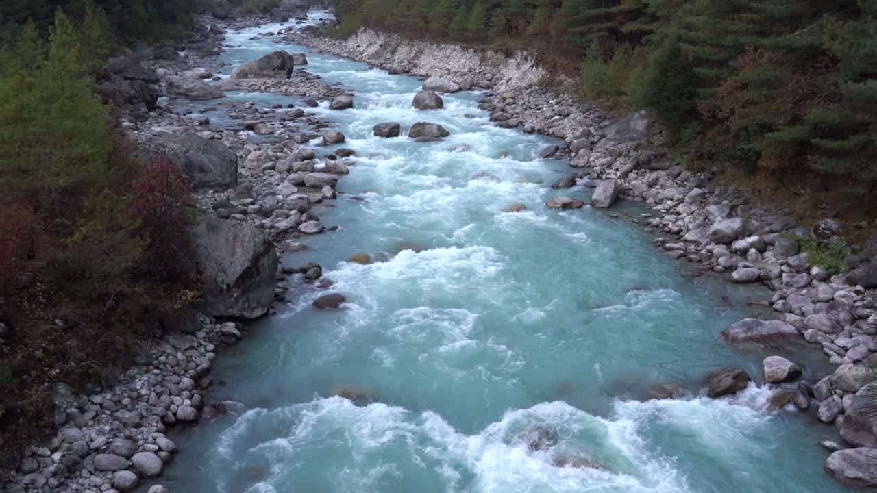 Una vista dall'alto di un fiume che scorre con acqua glaciale sui monti dell'Himalaya in Nepal.