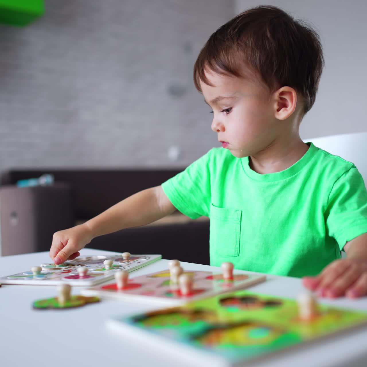 Bambino adorabile che gioca con i puzzle alla scrivania. Un bimbo concentrato è impegnato con un gioco a casa. Sfondo sfocato