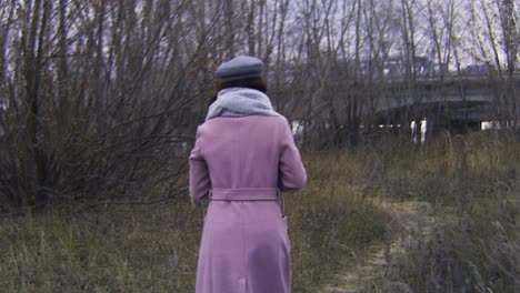 woman walking in an abandoned area near a bridge during autumn