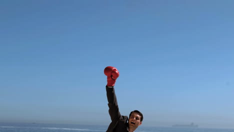 atractivo hombre de negocios saltando con guantes de boxeo rojos