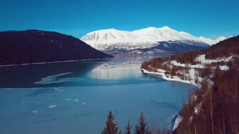 4k drone video of snow covered lakeside mountains in alaska during winter