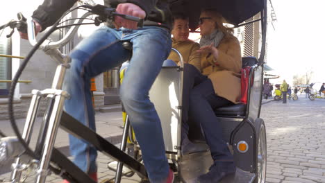 couple riding in bicycle taxi and talking to each other