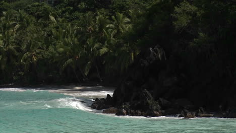 Las-Olas-Rompen-En-Una-Playa-De-Arena-Negra-Con-Formaciones-De-Lava-Negra