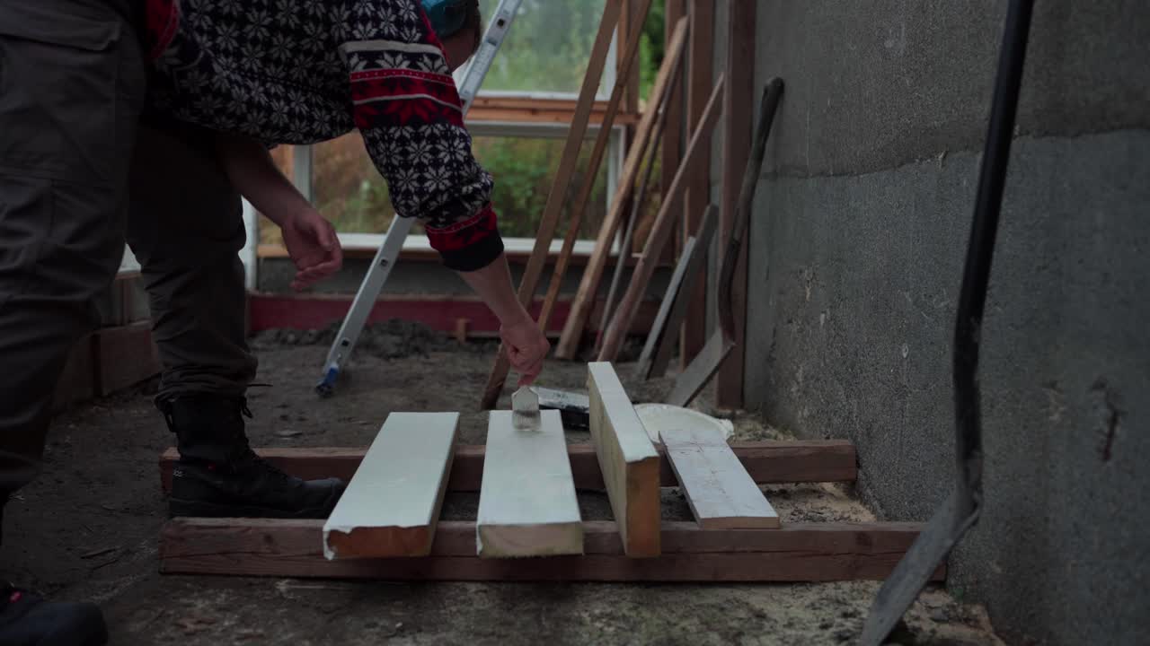 un hombre está pintando la madera que se utilizará para la construcción de un invernadero en indre fosen, noruega - de cerca