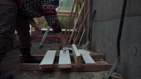 a man is painting the wood to be used for the construction of greenhouse in indre fosen, norway - close up