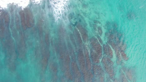 waves crashing near tropical island aerial top down