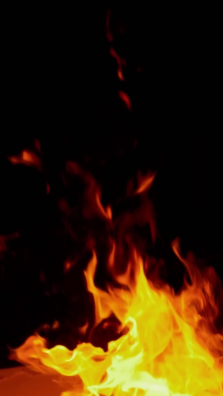 Splendida ripresa 4K senza soluzione di continuità di un falò dettagliato con vivaci fiamme arancioni e rosse su braci intense, isolato su uno sfondo nero puro. Perfetto per fusione, compositing e atmosfera
