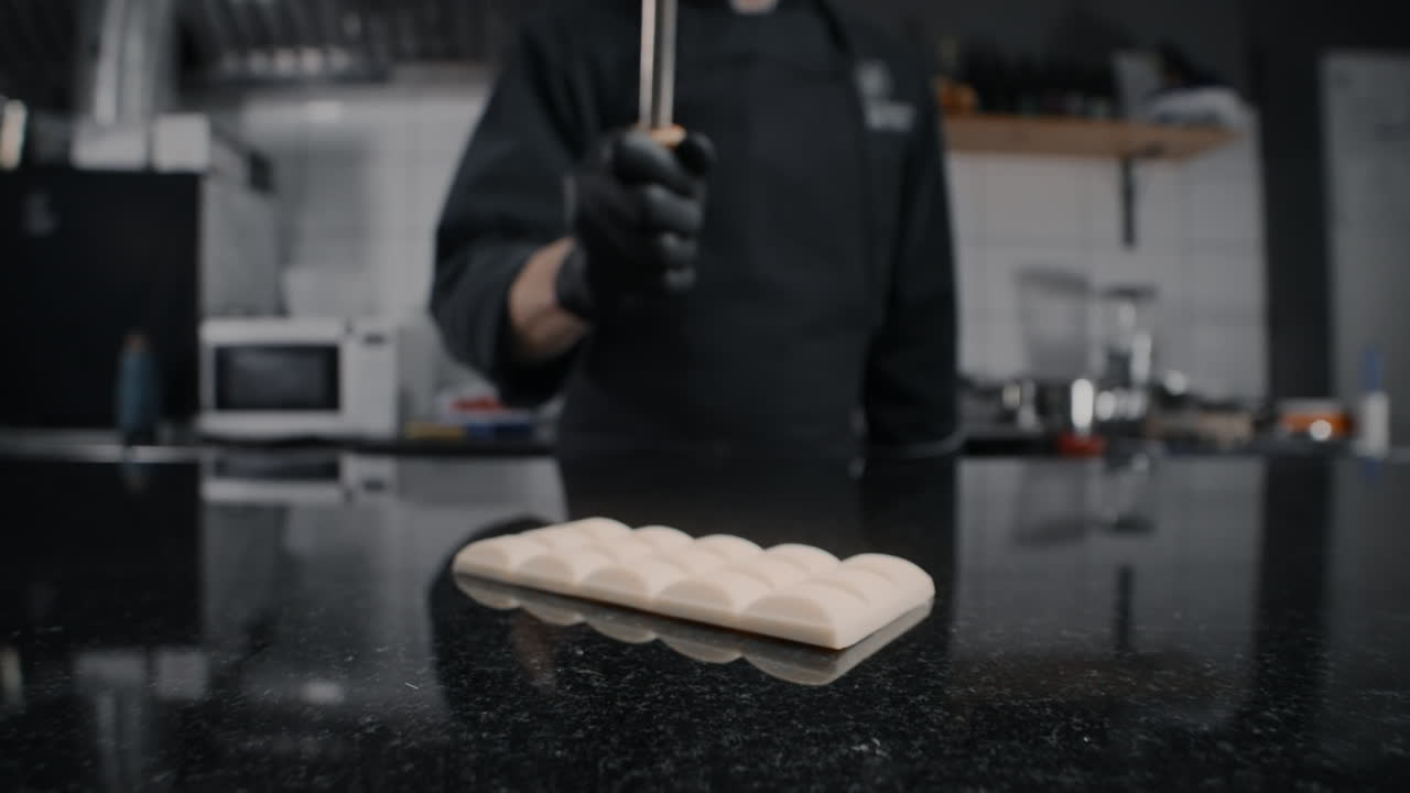 Chef che sminuzza cioccolato bianco con un martello