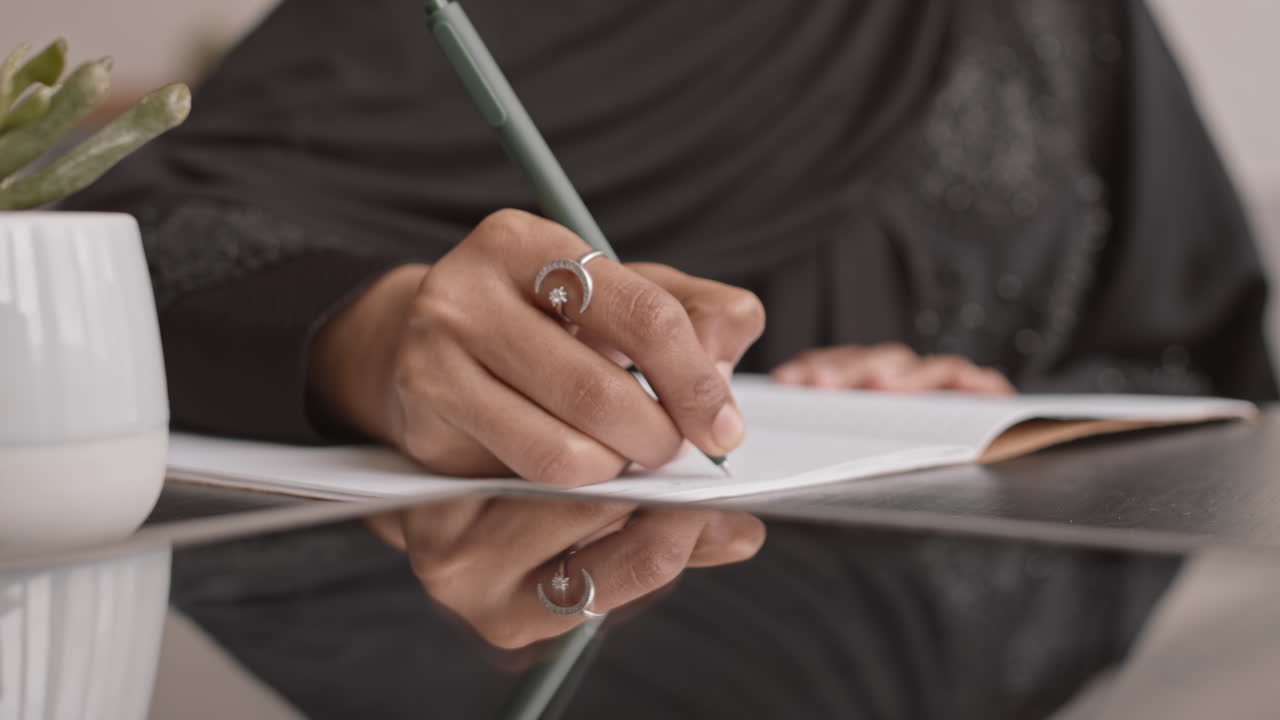 Hands of Muslim Woman Writing in Copybook