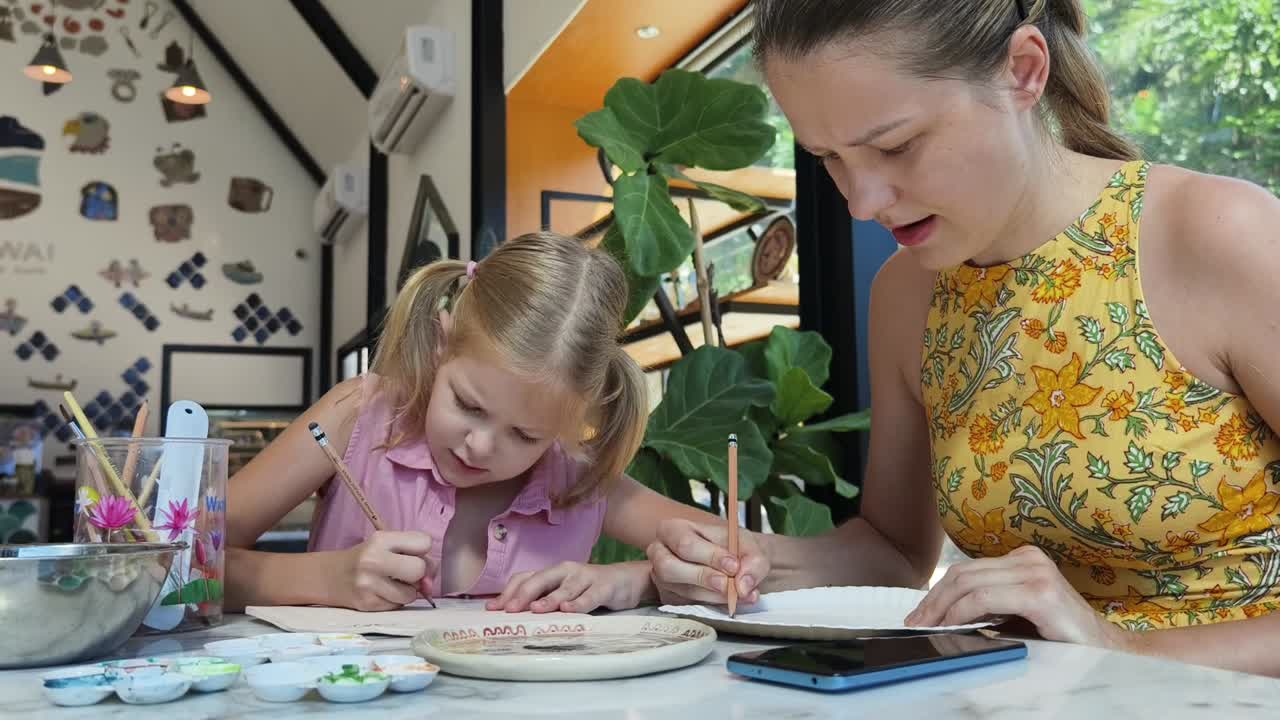 madre e hija pintando cerámica en un café