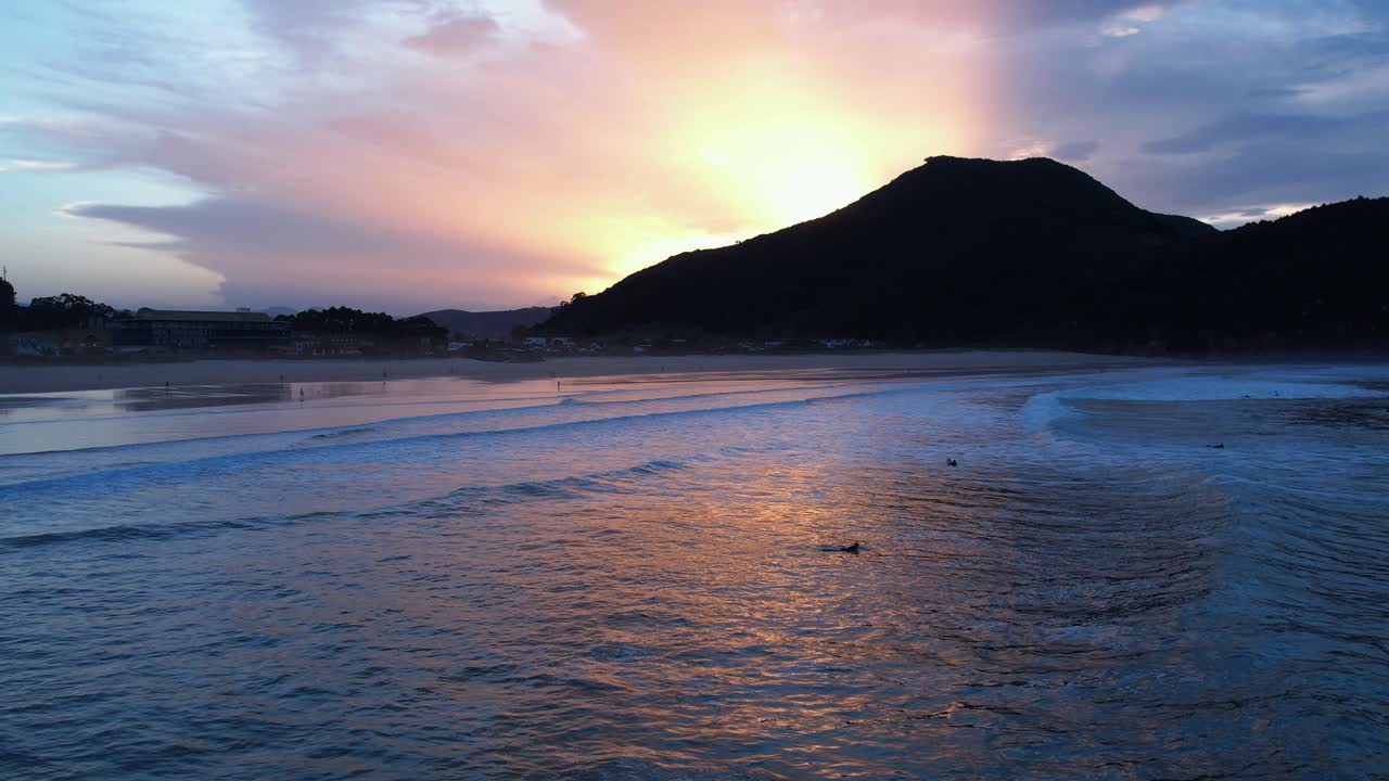 puesta de sol vista aérea de la playa de berria en cantábrico, españa con algunos surfistas en el agua