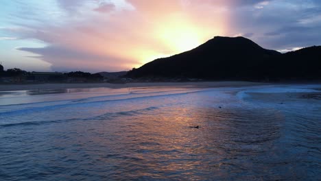 sunset aerial view of berria beach in cantabarian, spain with some surfers in the water