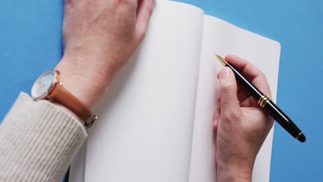 handschrift mit stift auf buch mit kopierraum auf blauem hintergrund in langsamer bewegung