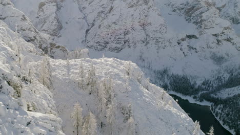 Breath-taking-aerial-view-establishing-over-snow-covered-mountain-forest-slopes-reveal-Italian-Lago-Di-Braies-lake-South-Tyrol-Dolomites