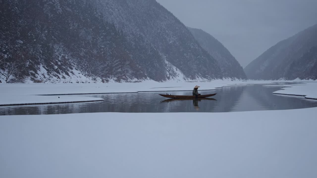 A serene winter landscape video captures a lone boat on a snowy river, framed by mountains