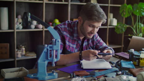 Leather-manufacturer-looking-at-new-model-of-leather-wallet-at-home-workshop