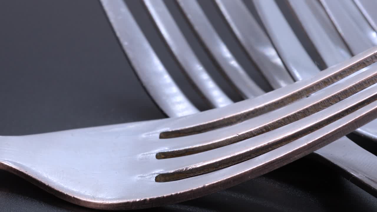 검정색 배경에 있는 일부 강철 포크의 세부 샷, 회전 동작