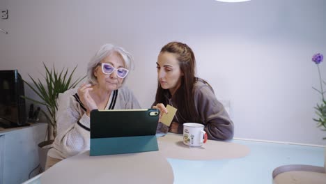 woman and senior woman using tablet to shop online with credit card