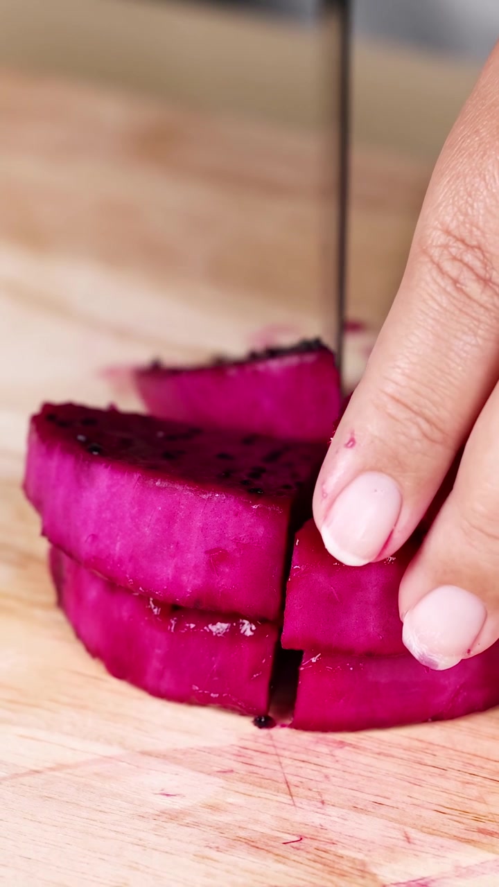 Hand slicing dragon fruit into neat pieces