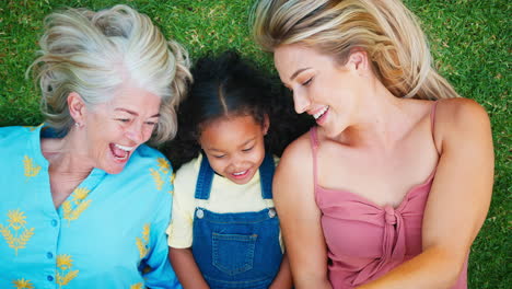 Overhead-Shot-Of-Multi-Generation-Female-Family-Lying-On-Grass-Taking-Selfie-On-Mobile-Phone