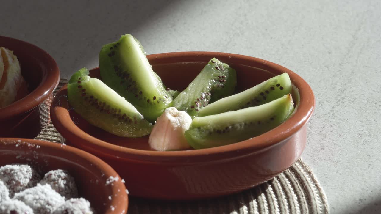 Fette fresche di kiwi verde disposte in una tradizionale ciotola di terracotta, evidenziando opzioni di snack vegetariani sani e ingredienti naturali per una dieta equilibrata