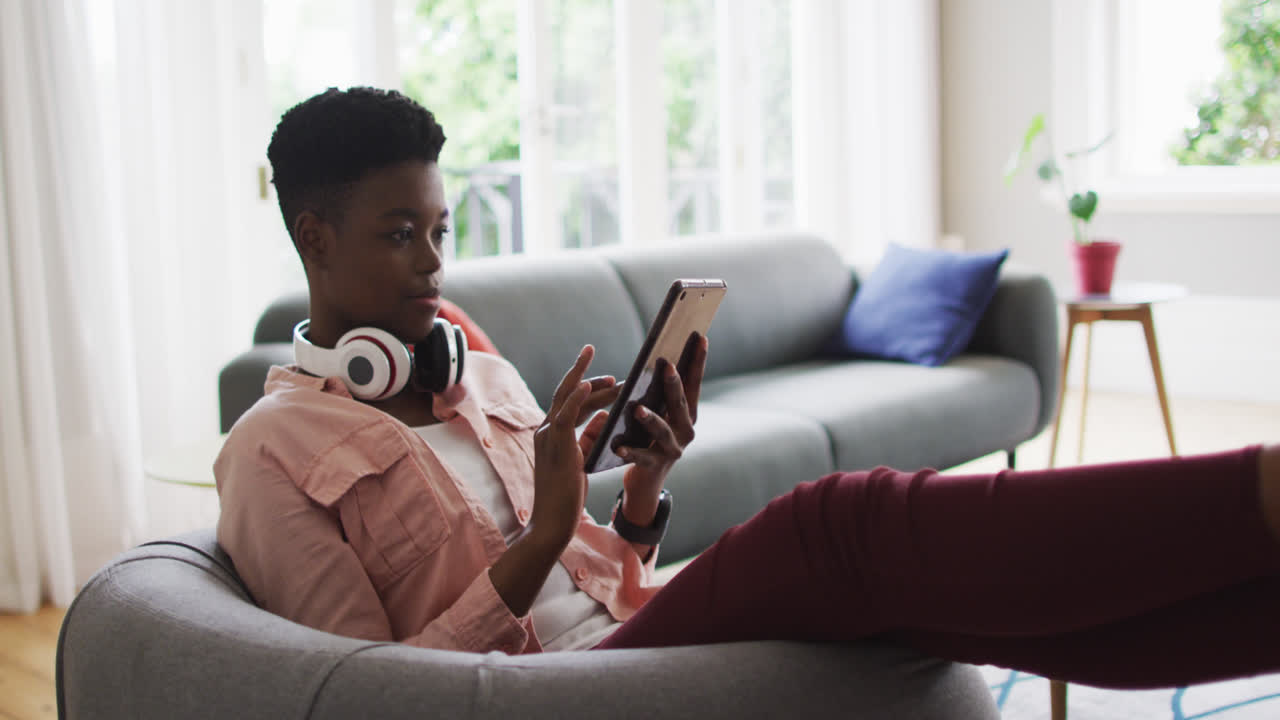 African american woman using digital tablet while sitting on the couch at home