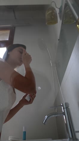 mujer aplicando crema para la cara en el baño
