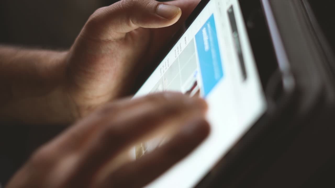 Shooted in slow motion showing man's hands browsing social media or playing with a mobile tablet at evening