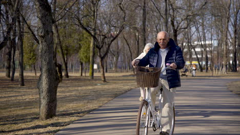 front view of a senior couple riding bikes in the park on a winter day