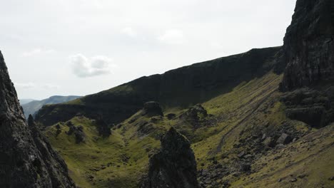 Aerial-view-winding-through-Scotland's-Storr-hillside-to-reveal-Loch-Leathan-in-the-distance