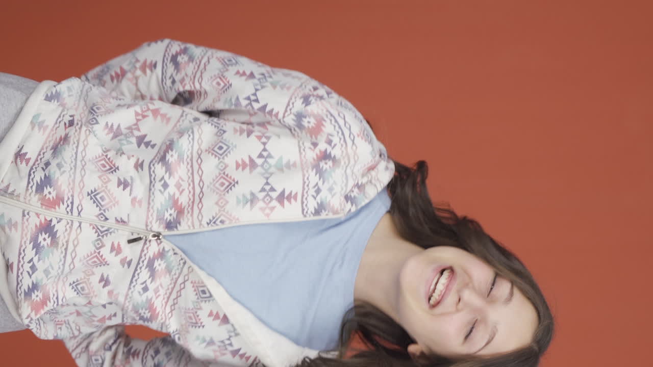 카메라를 위해 귀여운 몸짓을 하는 젊은 여성의 수직 비디오.