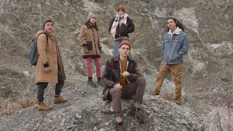 grupo de amigos adolescentes vestidos com roupas de inverno posando olhando para a câmera, sentado e em pé na montanha 1