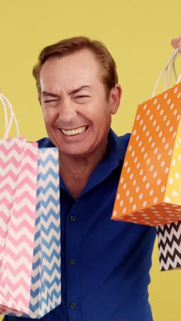 excited man holding colorful shopping bags