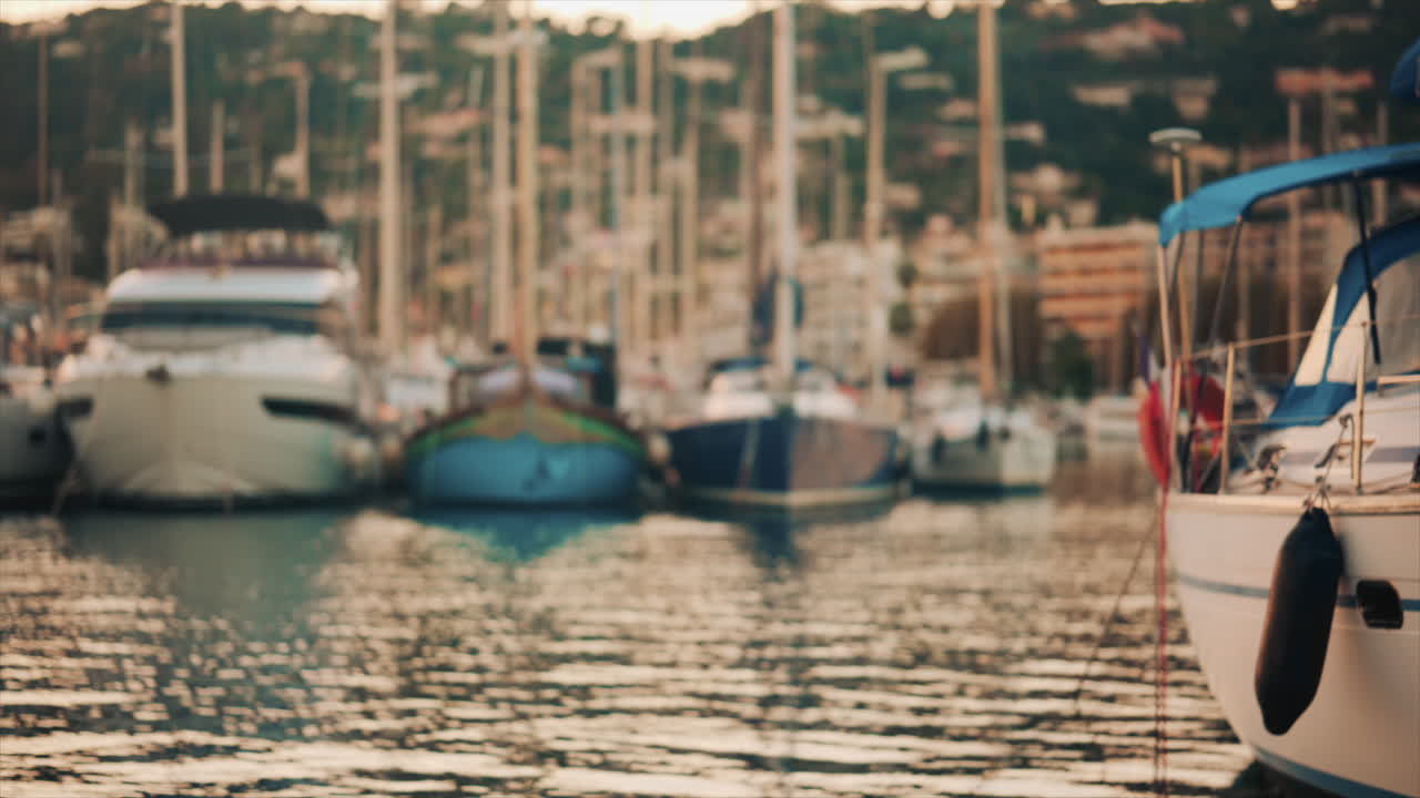 Elegant sailboats lined up in a marina during golden hour, calm water reflecting the evening sun