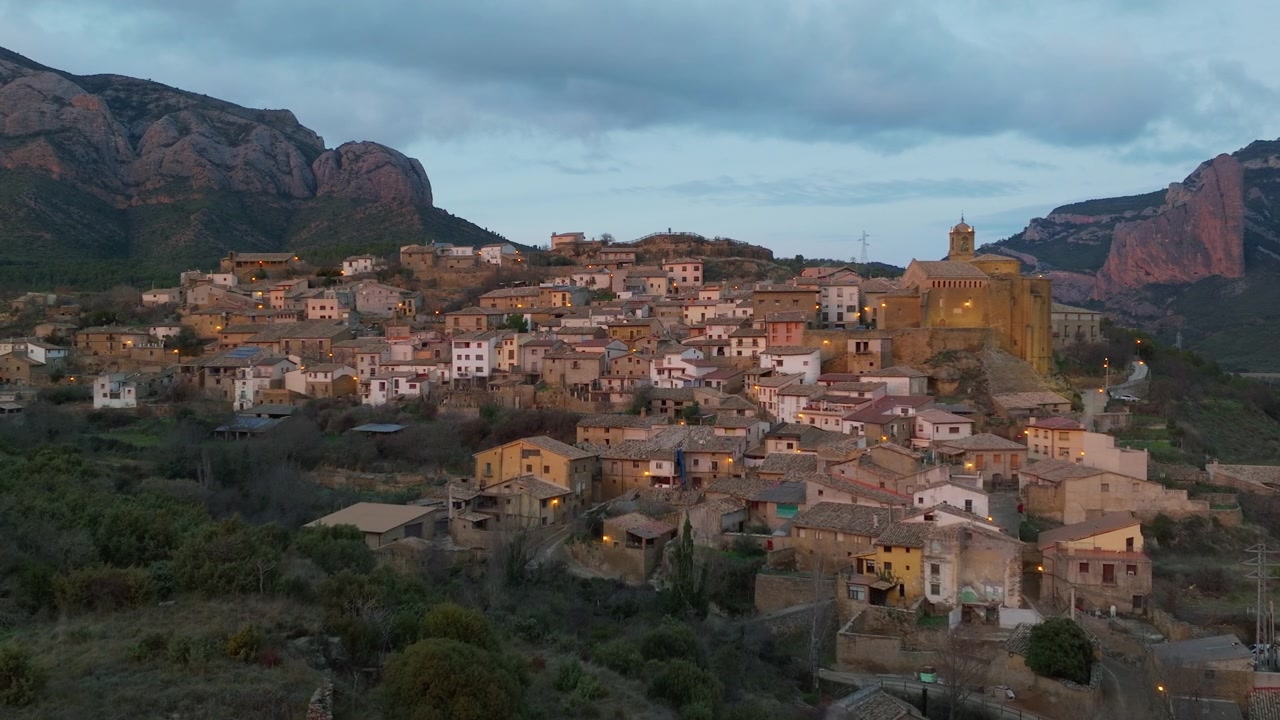 Pueblo español entre formaciones rocosas rojas al crepúsculo