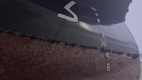 downward camera view reveals blue mussels and biofouling on ship hull near bow. needs cleaning work