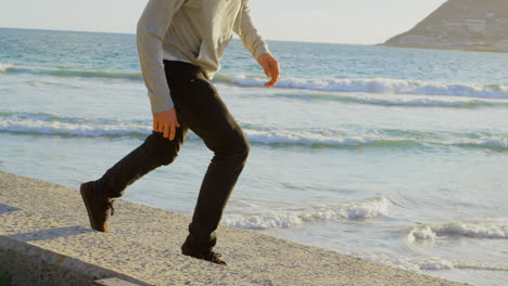 seitensicht eines jungen kaukasischen mannes, der einen skateboard-trick auf dem bürgersteig am strand 4k übt