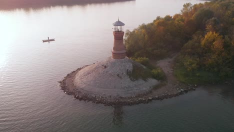 Umlaufendes-Filmmaterial-Um-Den-Alten-Steinernen-Leuchtturm-An-Der-Donau-Mit-Sonnenuntergang-Im-Hintergrund-Und-Erstaunlichen-Herbstfarben-Im-Wald