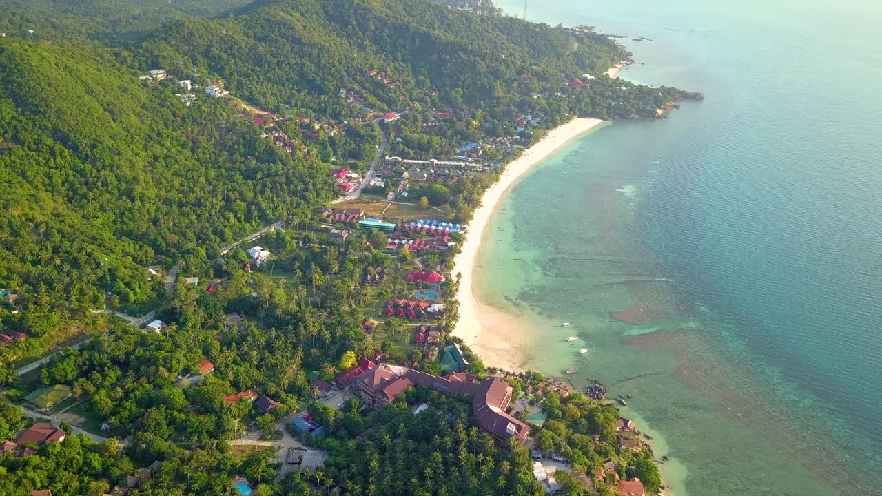 un dron aéreo de 4k empuja la toma de la playa de ensalada en koh phangan en tailandia con barcos de pesca, agua verde azulado, coral y selvas verdes