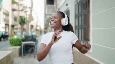 african american woman listening to music and dancing at street