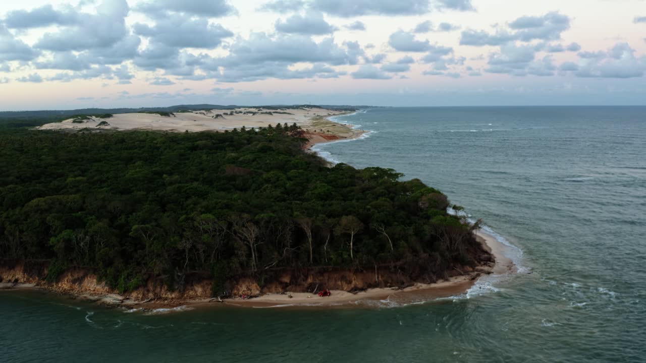 Right trucking aerial drone shot of the tropical Malemb&aacute; beach with dense jungle and golden sand dunes where the Guara&iacute;ras Lagoon meets the Atlantic Ocean in Tibau do Sul, Rio Grande do Norte, Brazil