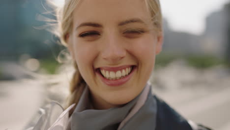 retrato en primer plano de una joven rubia atractiva sonriendo feliz alegre en una ciudad ventosa disfrutando del estilo de vida urbano con bufanda